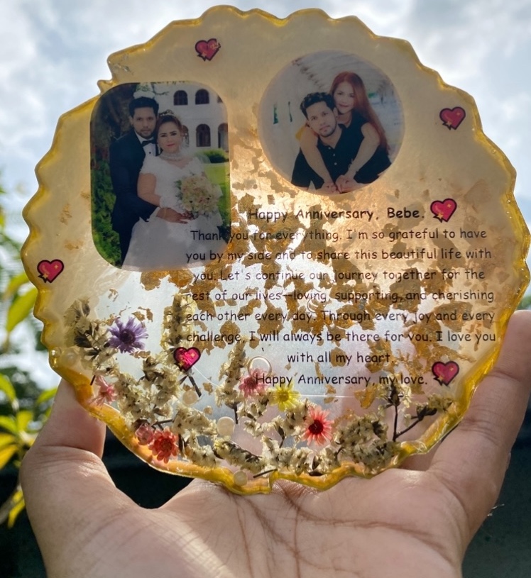 A circular gold-fleck resin anniversary frame with two couple photos and a Happy Anniversary message, made by Resin Gallery by Suu