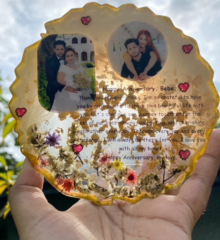 A circular gold-fleck resin anniversary frame with two couple photos and a Happy Anniversary message, made by Resin Gallery by Suu