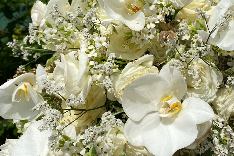 A fresh white wedding bouquet of roses and orchids, ready to be preserved