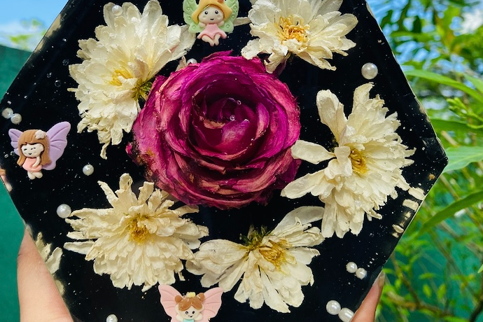 A magenta rose and white blooms preserved in a glossy, hand-polished black resin piece