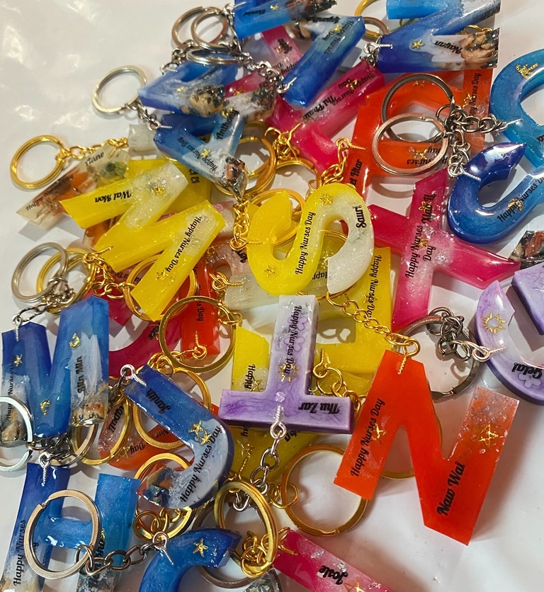 A pile of colourful personalized resin letter keychains made by Resin Gallery by Suu