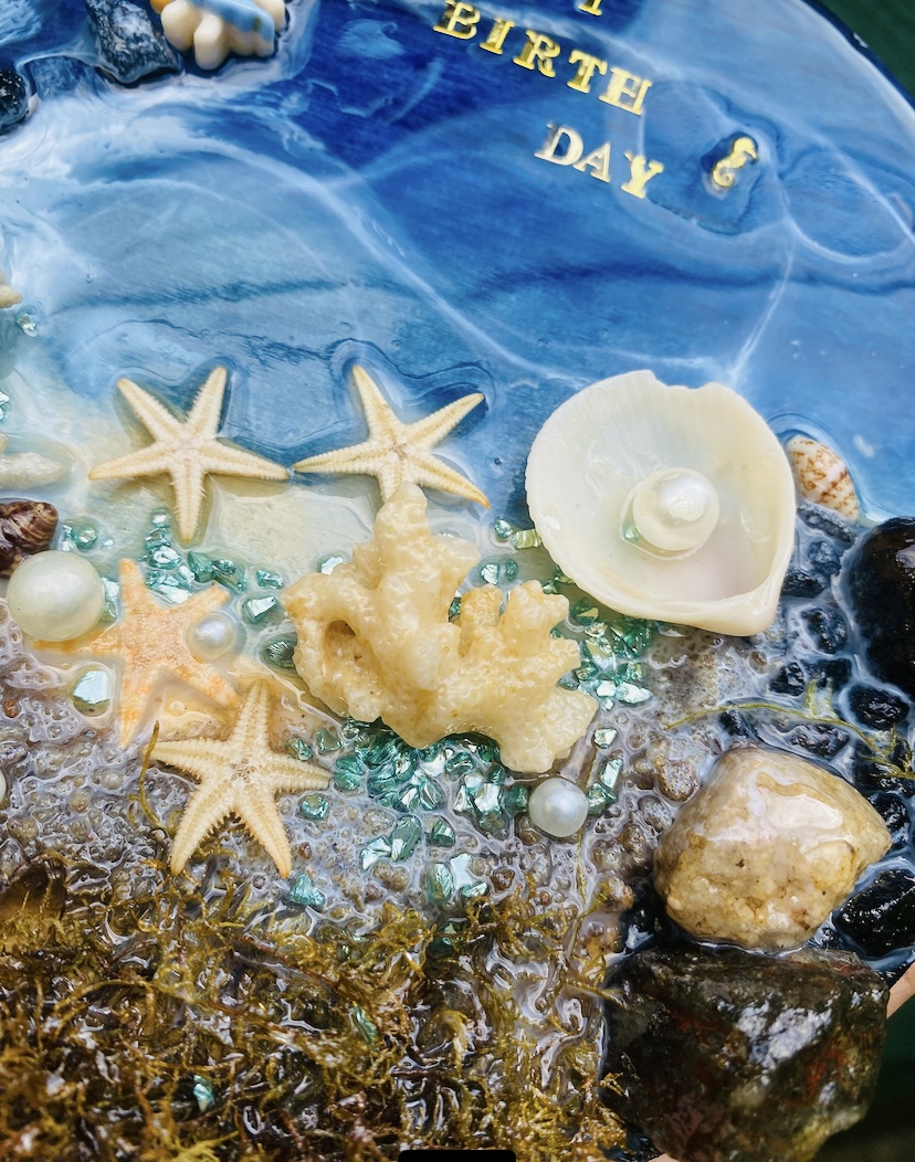 An ocean-themed resin piece with seashells and a golden starfish