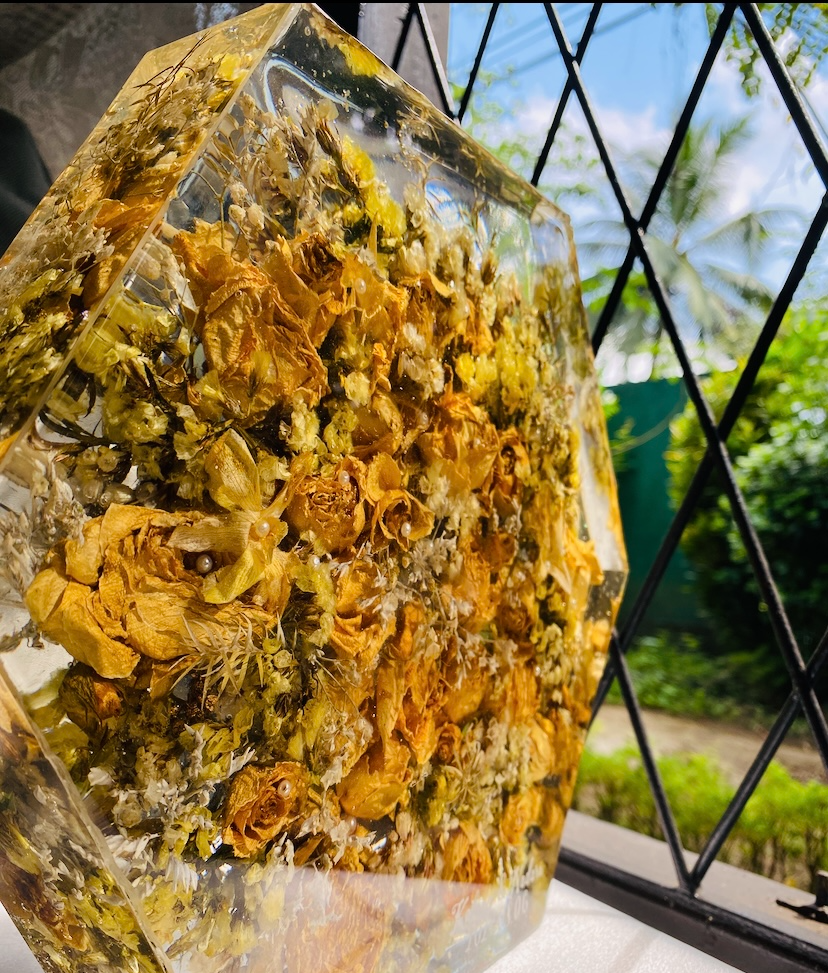 Dried roses and baby's breath preserved inside a clear hexagon resin block