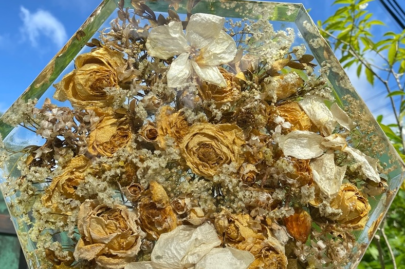 Dried roses and blooms arranged and set inside a clear resin keepsake